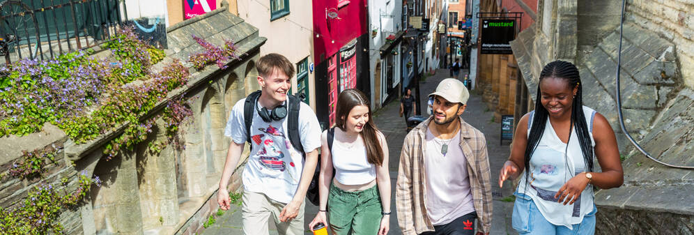 Four students walking up the Christmas Steps in central Bristol on a sunny day.